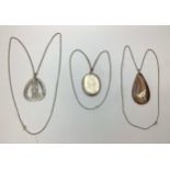 Three various silver pendants and chains including a large oval shaped silver locket, a large pear
