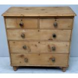 A Victorian stripped and waxed pine chest of two short and three long graduated drawers, with turned