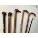 Five various walking sticks including two Greek examples, one carved with a hand holding a male head