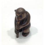 A Japanese Meji period hand carved boxwood netsuke of a monkey playing a pipe, signed to base with