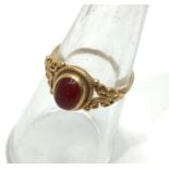 A 9ct yellow gold dress ring set with an oval orange cabochon cut stone in a rub over setting,