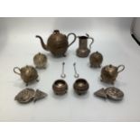 An Indian white metal six piece condiment set with embossed foliate decoration, together with a