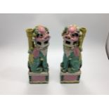 A pair of Chinese porcelain temple dog candlesticks modelled atop pedestals, painted in polychrome