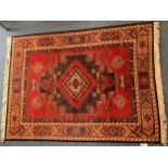 A hand-woven tufted, Afghan rug, with central diamond medallion to a red ground, with guls and