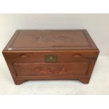 An Oriental camphor lined carved hard wood blanket box / trunk, carved with scenes of people and