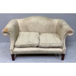 A hump-back two-seater sofa, for re-upholstery, with scrolled arms and two loose cushions, raised on