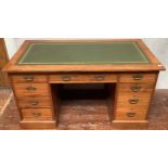 An Edwardian walnut pedestal desk with gilt tooled green leather scribe, central frieze draw flanked