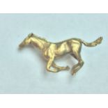 A solid 9ct yellow gold 'galloping horse' brooch, weighing 9.9 grams, hallmarked.