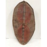 A Maasai shield Kenya hide with painted geometric decoration in earth red and black, with a wooden