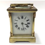 A French brass cased carriage clock with black roman numerals to white ground, bevelled glass front,