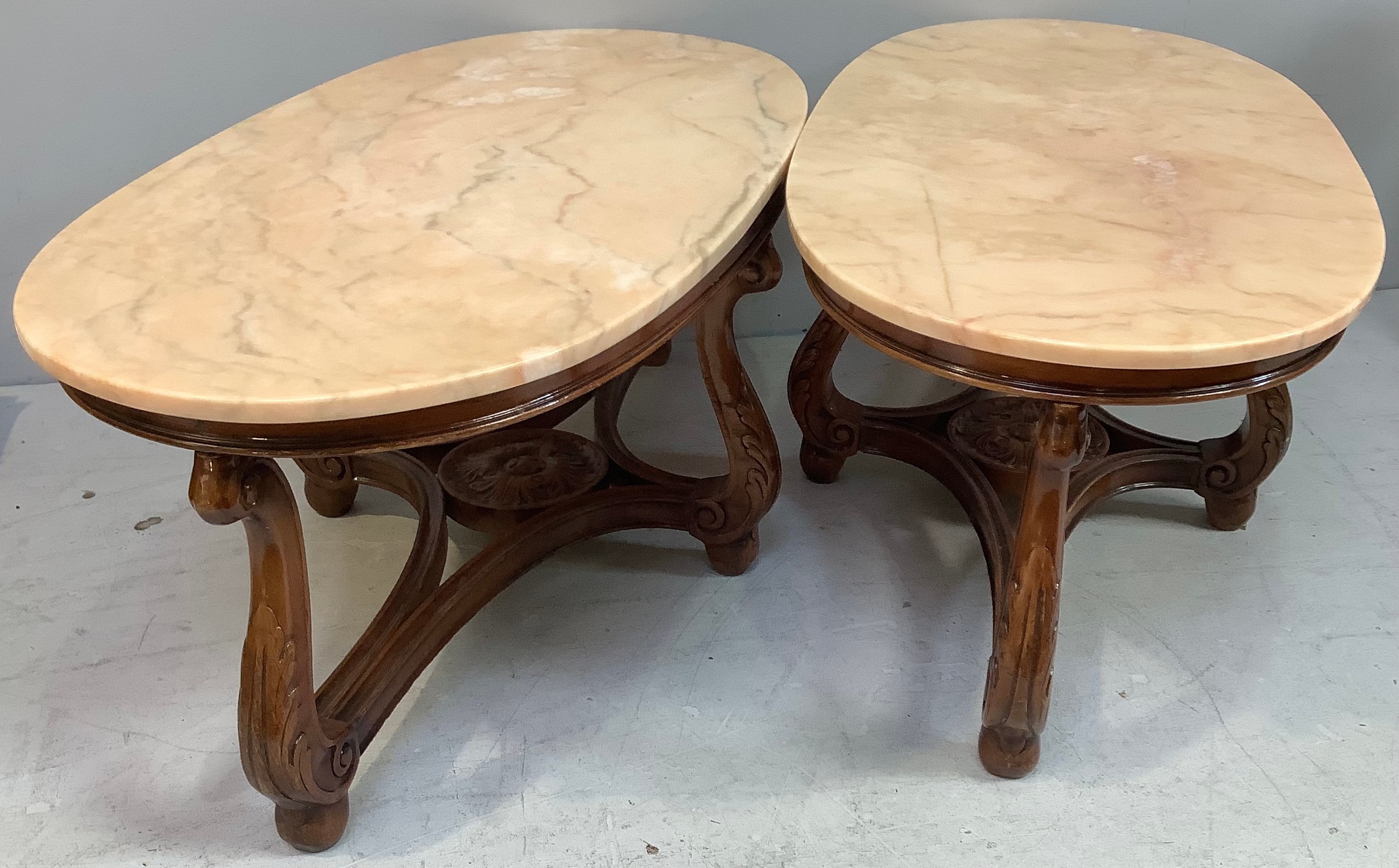 A pair of heavy oval salmon pink marble topped coffee tables, (From 'The Queen's Hotel, Southsea),