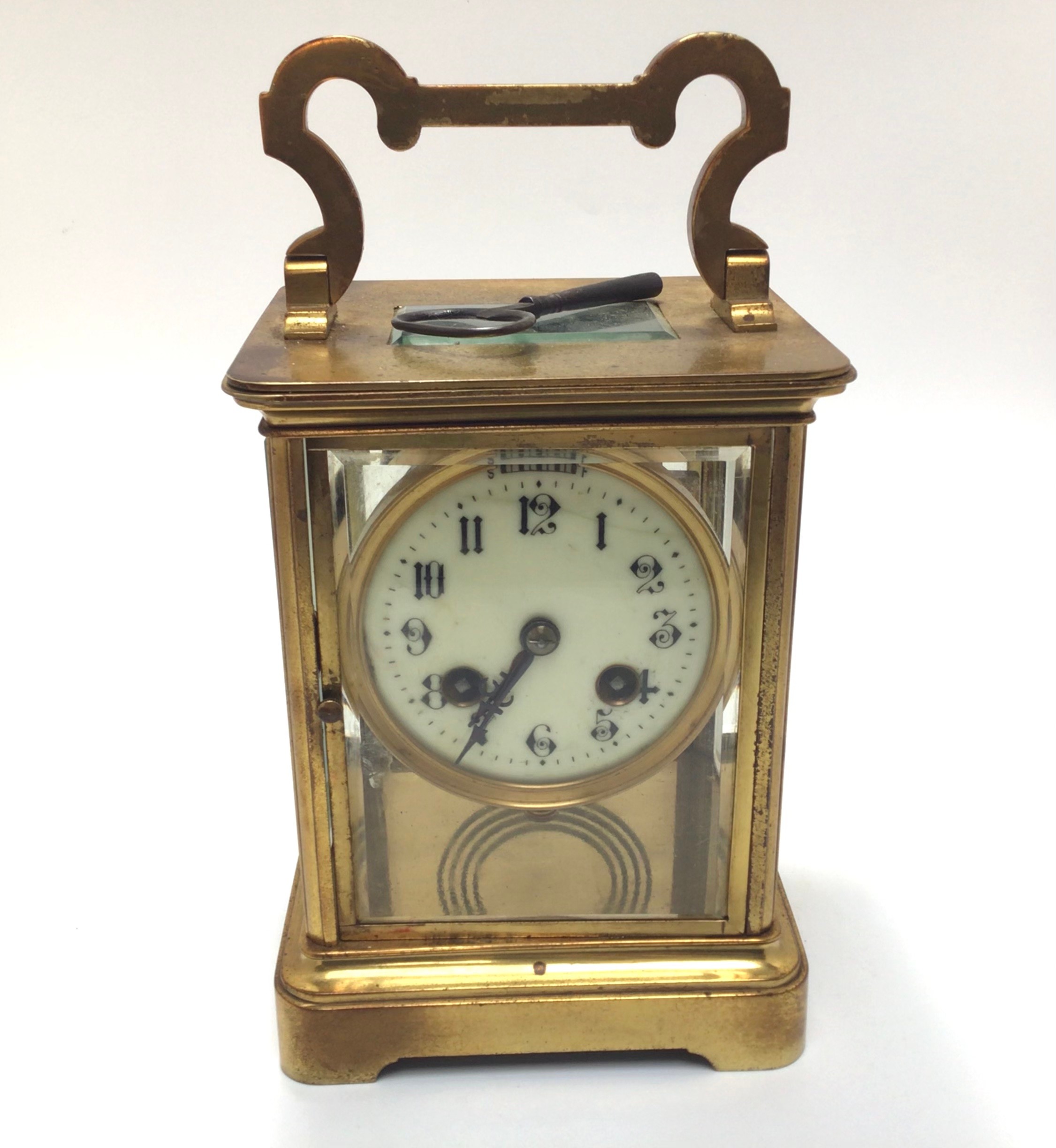 A large brass cased eight day carriage clock with black arabic numerals to circular cream enamel