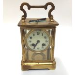 A large brass cased eight day carriage clock with black arabic numerals to circular cream enamel