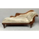 A Victorian walnut framed chaise lounge with beige upholstery, raised on turned supports to brass