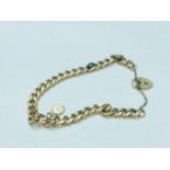 A 9ct yellow gold curb link bracelet with heart padlock and mini St Christopher pendant attached,