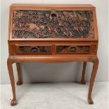 An Oriental carved teak bureau, the fall front profusely carved with a scene of warriors on