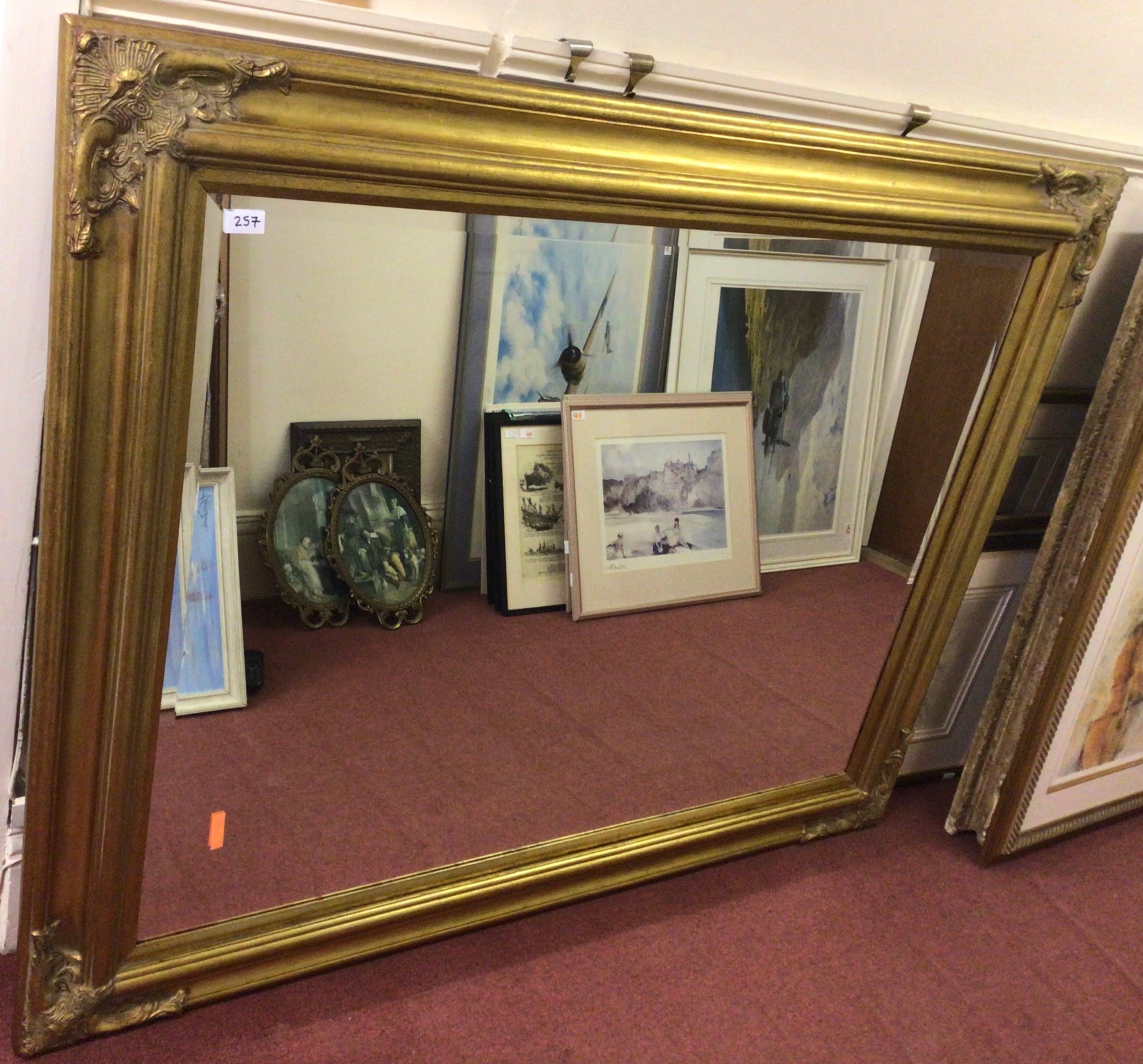 A very large gilt framed bevelled glass mirror carved with stylised spandrels, 147 x 118cm