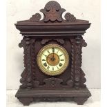 A 19th century carved and stained wooden mantel clock with shaped pediment, gilt chapter ring, cream