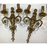 A pair of gilt brass twin-branch wall lights each with a cherub playing pipes, scrolled branches