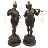 A pair of bronze figures of guardsmen with axes over their shoulders and swords at their sides,