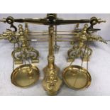 A large pair of brass scales with inset weights, together with a pair of brass fire dogs and a brass