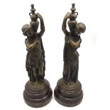 A pair of bronze classical maidens carrying urns on their shoulders, raised on turned circular