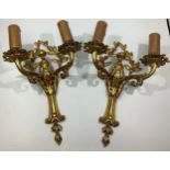 A pair of gilt brass twin-branched wall lights, with putto figures, scrolled arms with sconces, 33cm