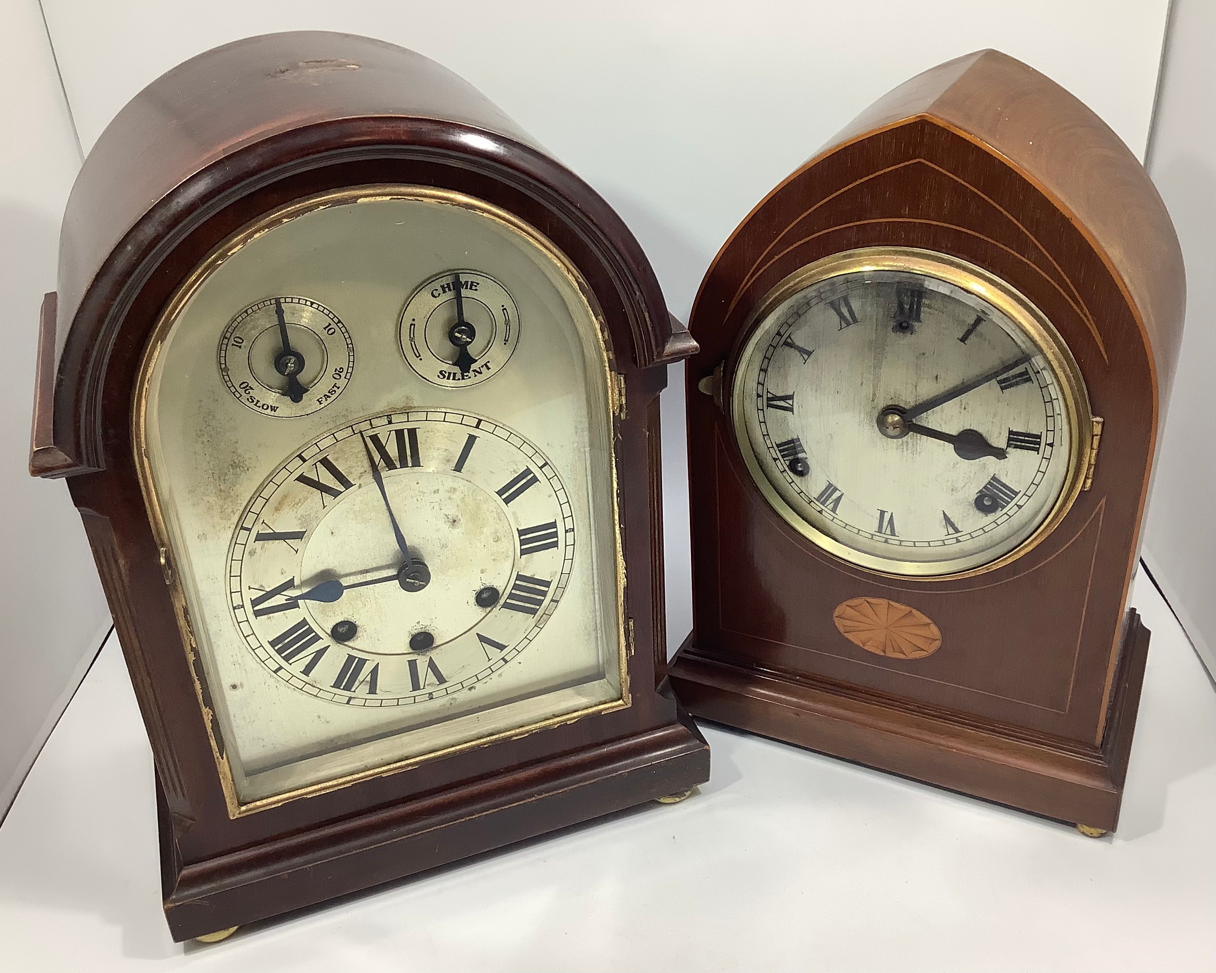 A mahogany cased mantel clock with arched top, silvered dial with Roman numerals, slow-fast and