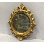 An oval bevelled mirror in carved and gilded, leaf moulded frame, 50cm including frame