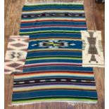 A very large colourful Navajo blanket with multi-coloured stripes and central medallion, fringed