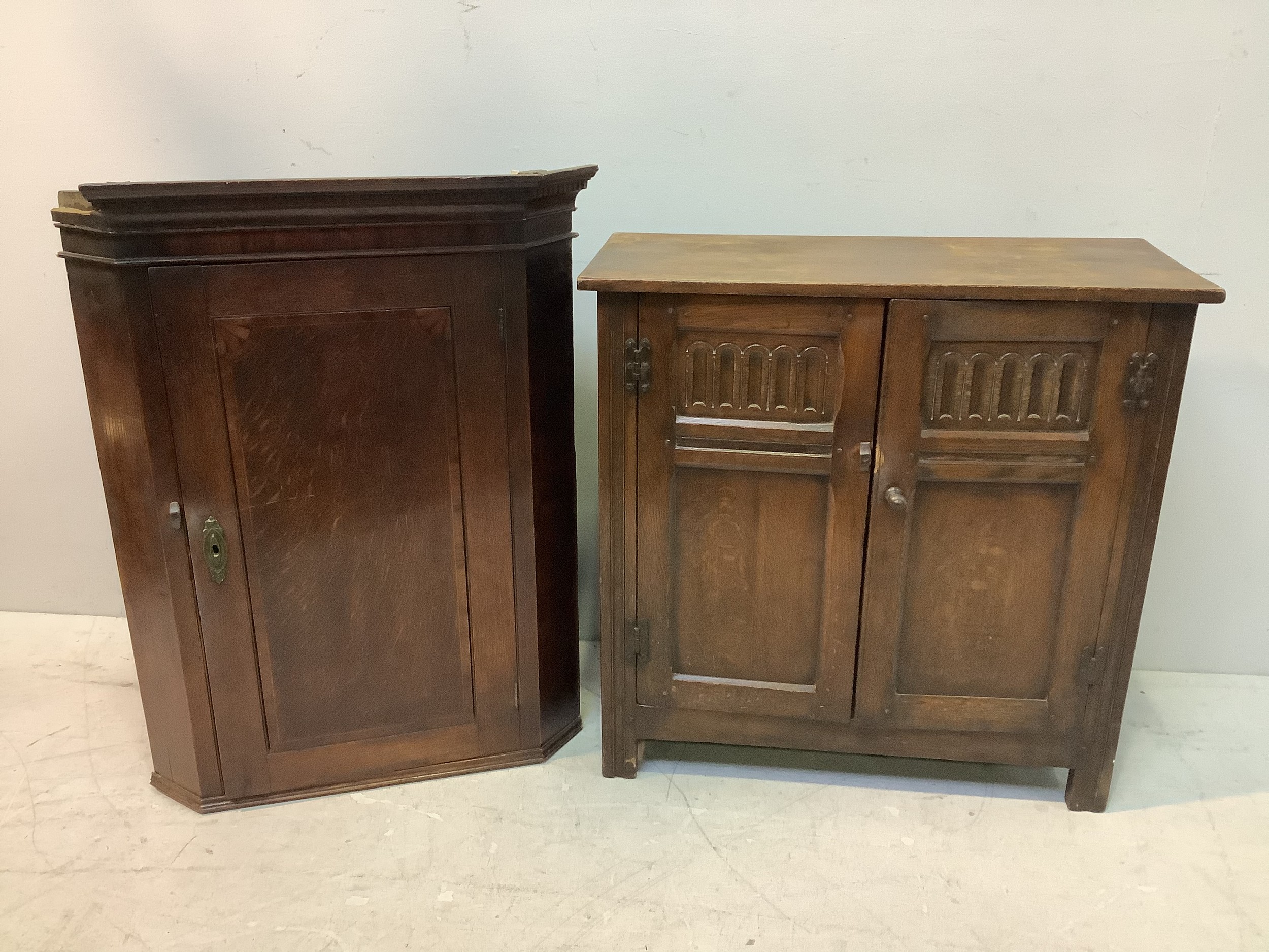 An Edwardian oak cupboard with a pair of arcade-carved front panel doors enclosing three inner