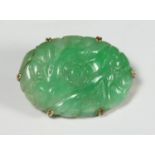 A 14ct gold and floral-carved oval jade brooch, 2.5cm diam