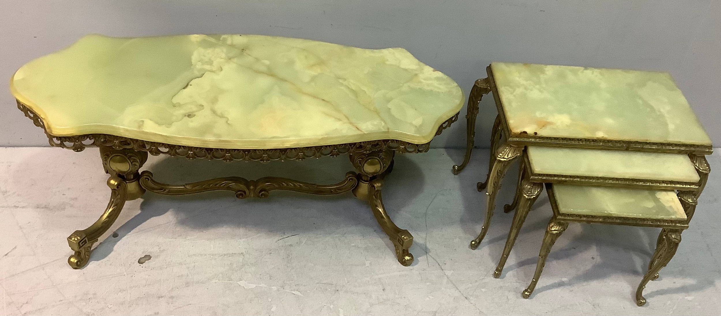 An Italian sculptured oval onyx coffee table on an ornate brass base and filigree border together