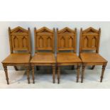 A set of four gothic style oak hall chairs with arched backs with twin acorn finials, the backs