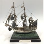A silver model of HMS Endeavour fully rigged, raised on green marbled base and further raised on