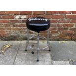 A Gibson guitar stool with logo to seat and raised on four metal supports, 62cm tall