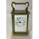 A brass cased carriage clock with black roman numerals to white ground, bevelled glass front, sides,