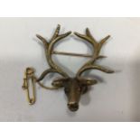 A yellow gold stag's head brooch with textured finish and ruby coloured eyes and gold safety