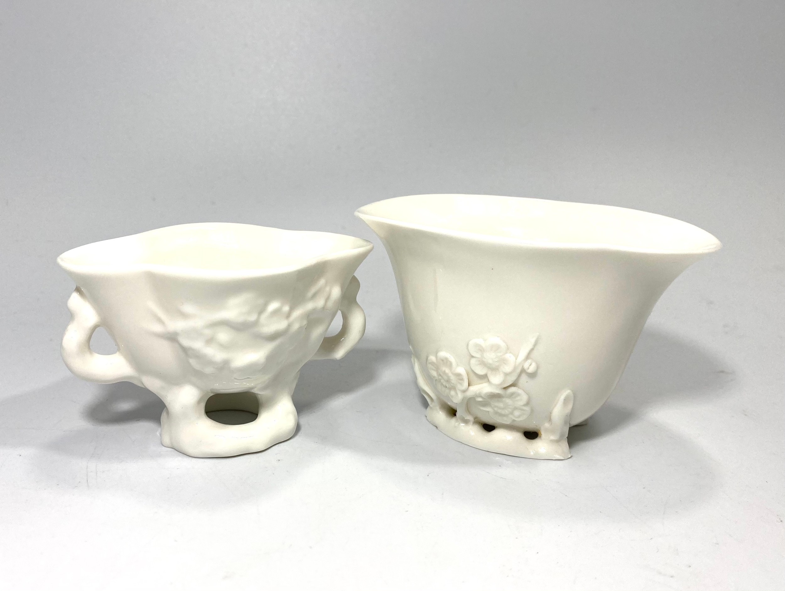 Two various blanc-de-chine Chinese porcelain libation cups, each moulded with peony blossom and