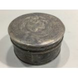 A Malaysian silver trinket box of squat cylindrical form, the lid and sides decorated with