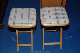 Two check-upholstered folding stools.