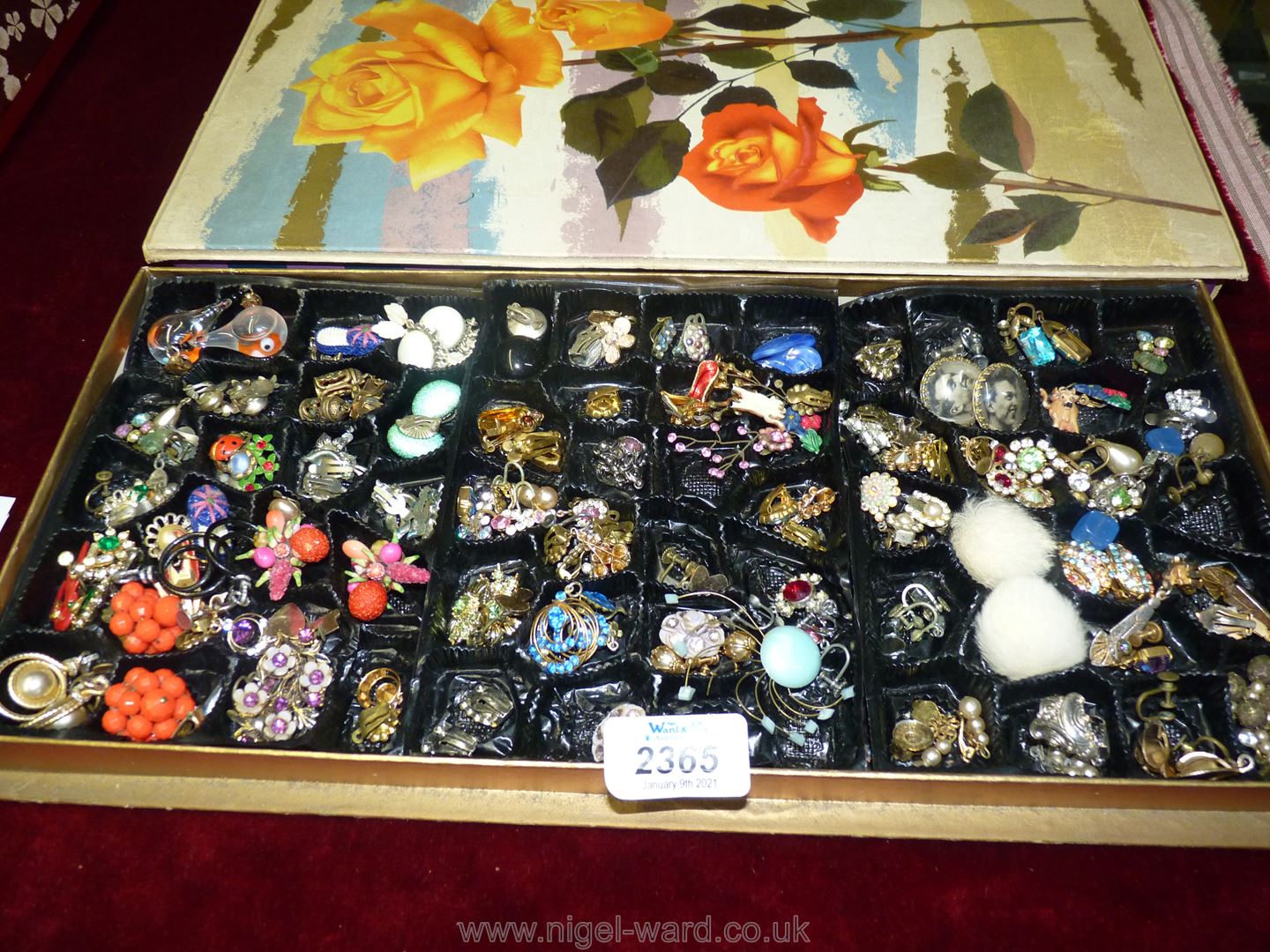 A vintage chocolate box containing vintage earrings including a pair of 'Tommy Steel' clip-ons and