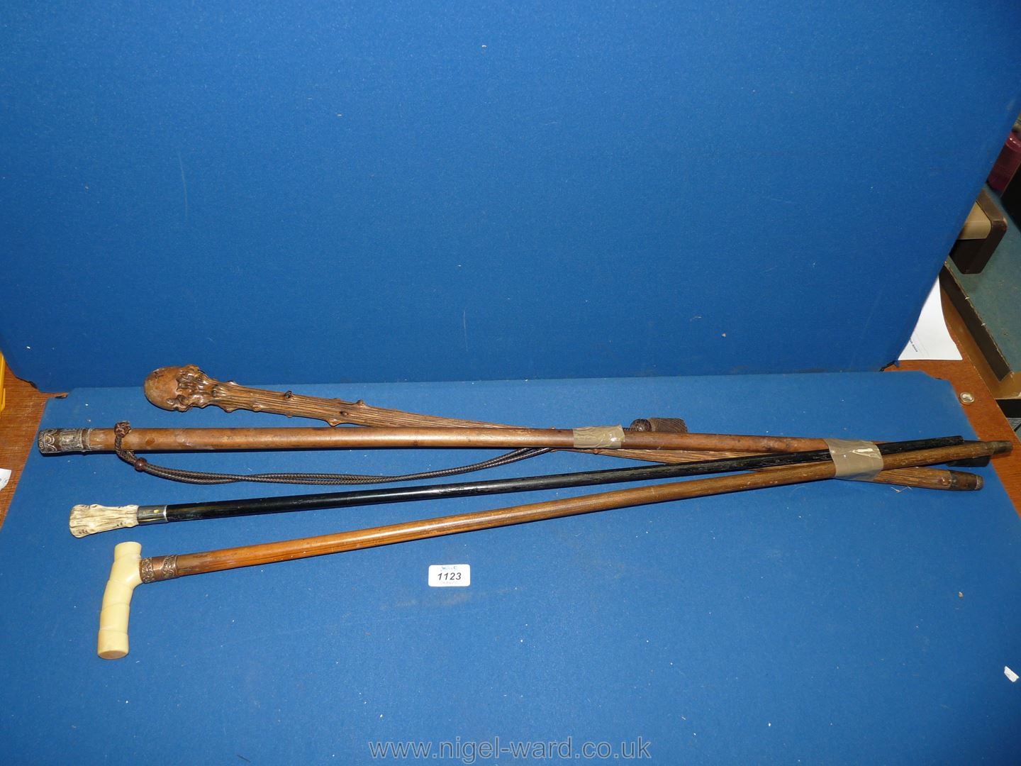 Four walking canes including one with leather thongs threaded through stick, copper collared,