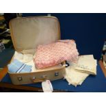 A suitcase of linen including red and white table cover, small bed cover, tray cloths, napkins etc.