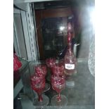 A cranberry glass aperitif decanter and five matching glasses.