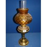 A brass oil lamp with reeded column and caramel brown shade.