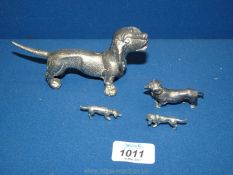 A family of white metal Dachshund ornaments plus one larger Dachshund.
