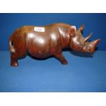 A large wooden carved Rhinoceros, 7 1/4'' high x 13 1/2'' long (ears a/f).