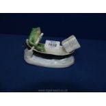 An early 20th century majolica novelty ashtray and matchbox holder modelled as a frog rowing a boat,