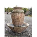 A large urn shaped concrete water feature with relief moulded cherubs complete with a winter cover,